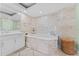 Luxurious bathroom features soaking tub, travertine tile, and white cabinetry at 2410 Harbourside Dr # 142, Longboat Key, FL 34228