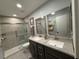 Bathroom featuring double sinks with granite counters and a glass-enclosed shower for modern convenience at 2465 Northside Dr # 604, Clearwater, FL 33761