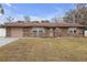 Charming brick home featuring a well-maintained lawn and attached garage on a bright day at 27103 Frampton Ave Ave, Brooksville, FL 34602