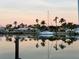 Scenic waterfront view featuring a sailboat and palm trees reflected in calm waters at sunset at 350 Pinellas Bayway S # 2, St Petersburg, FL 33715
