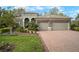 Charming home featuring a manicured lawn, stone accents, a brick driveway, and a two-car garage, exuding curb appeal at 3633 Cordgrass Dr, Valrico, FL 33596