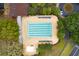Aerial view of a sparkling community pool with lounge chairs, complemented by trees, and nearby street adding to its appeal at 3633 Cordgrass Dr, Valrico, FL 33596