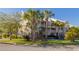Exterior view of a three-story condo with balconies, tropical landscaping, and a covered parking space at 418 Bahia Beach Blvd, Ruskin, FL 33570