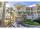 Exterior view of a three-story condo with balconies, a garage, tropical landscaping, and a paved driveway at 418 Bahia Beach Blvd, Ruskin, FL 33570