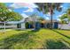 Landscaped front yard featuring a single story blue home, shade trees, a lawn, and a two car garage at 6208 Imperial Ky, Tampa, FL 33615