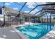 A backyard view showcasing an enclosed pool with covered patio seating and shade trees at 6208 Imperial Ky, Tampa, FL 33615