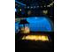 Evening view of a shimmering pool and lit fire pit, creating a cozy backyard ambience at 6208 Imperial Ky, Tampa, FL 33615