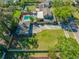 Expansive aerial view of a residence with a backyard pool, detached garage, well-manicured lawn, and lush surrounding greenery at 8205 Overlook Ne Pl, St Petersburg, FL 33702
