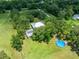 The aerial shot highlights the lawn, pool, trees, outbuildings, and a long driveway to the home at 9017 S County Line Rd, Lithia, FL 33547
