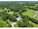 Aerial view shows home, lawns, outbuildings, and neighboring properties surrounded by tall trees at 9017 S County Line Rd, Lithia, FL 33547