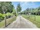 Long gravel driveway leads to a charming property surrounded by mature trees and lush greenery at 9017 S County Line Rd, Lithia, FL 33547