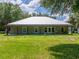 Ranch-style home with a metal roof and a charming covered porch overlooking a lush green lawn at 9017 S County Line Rd, Lithia, FL 33547