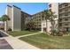 Condo building exterior with a lush green lawn, mature palm trees, and covered parking spaces at 9860 62Nd N Ter # 1051, St Petersburg, FL 33708