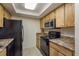 Functional kitchen featuring wood cabinets, solid-surface countertops, and black appliances at 9860 62Nd N Ter # 1051, St Petersburg, FL 33708