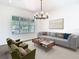 Inviting living room with large windows, modern chandelier and neutral colored decor at 10818 Breaking Rocks Dr, Tampa, FL 33647