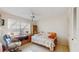 Sunlit bedroom with a ceiling fan, built-in desk, and a view from the window with blinds at 11135 Carriage Hill Dr # 5, Port Richey, FL 34668