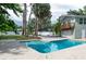 Backyard pool view with lush landscaping, tall palm trees, privacy fence, and home with second story deck at 1320 Coral S Way, St Petersburg, FL 33705