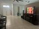 Open living area with tile floors, large TV, and access to the front door and other rooms at 14305 Tennyson Dr, Hudson, FL 34667