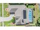 Aerial view of a home with a pool and solar panels, surrounded by a well-kept lawn and mature trees at 16808 Woburn Ln, Lutz, FL 33549