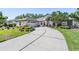 Charming home featuring a lush landscaped yard, a circular driveway, and a blue front door at 16808 Woburn Ln, Lutz, FL 33549
