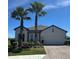 Beautiful single-story home boasts a brick driveway, two-car garage, manicured landscaping, and two mature palm trees at 1904 146Th E Ter, Parrish, FL 34219