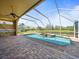 Inviting screened-in pool area with brick patio, overlooking a peaceful pond and greenery at 19230 Wind Dancer St, Lutz, FL 33558