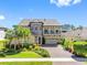 Two-story home featuring a brick driveway, manicured lawn, mature palm trees, and stone accents on the facade at 19412 Lonesome Pine Dr, Land O Lakes, FL 34638