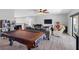 Spacious living room featuring modern furniture, hardwood flooring, a ceiling fan, and a pool table at 19412 Lonesome Pine Dr, Land O Lakes, FL 34638