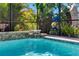Pool with rock waterfall feature, planter boxes, and lush landscaping behind enclosure at 19412 Lonesome Pine Dr, Land O Lakes, FL 34638