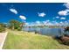 Spacious backyard boasting a dock, lush green grass, lake views, and mature landscaping at 22322 Tennyson Ave, Port Charlotte, FL 33954