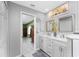Bright bathroom features a double vanity with white cabinets, a marble countertop, and modern fixtures at 22322 Tennyson Ave, Port Charlotte, FL 33954