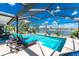 Enclosed screened lanai featuring a sparkling pool with lounge chairs and a picturesque lake view at 22322 Tennyson Ave, Port Charlotte, FL 33954