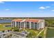 Beautiful condo building with a red tile roof and lovely landscaping, near a pond and parking area at 234 Mariner Dr # 234, Tarpon Springs, FL 34689