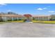 Community clubhouse entrance with a red tile roof, manicured landscaping, and ample parking at 234 Mariner Dr # 234, Tarpon Springs, FL 34689