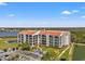 Low-angle view of multi-story condo with manicured grounds, parking and tranquil lake at 234 Mariner Dr # 234, Tarpon Springs, FL 34689