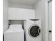 Bright laundry room features white front load washer, dryer, and wall-mounted cabinets above at 24941 Ravello St, Land O Lakes, FL 34639