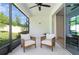 Covered patio featuring two chairs and fan with sliding glass doors to the interior at 2516 Leafwing Ct, Palm Harbor, FL 34683