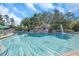 Large community pool with a waterfall feature, lounge chairs, umbrellas, and lush greenery at 36750 Us 19 N # 2763, Palm Harbor, FL 34684