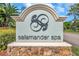 Community sign with salamander logo against a backdrop of lush greenery on a bright, sunny day at 36750 Us 19 N # 2763, Palm Harbor, FL 34684