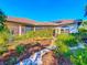 Home exterior with a tiled roof, solar panels, screened lanai, a decorative garden archway and lush landscaping at 4499 Chase Oaks Dr, Sarasota, FL 34241