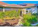 Home exterior with a tiled roof, solar panels, screened lanai, a decorative garden archway and lush landscaping at 4499 Chase Oaks Dr, Sarasota, FL 34241