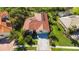 Aerial view showcasing a well-maintained home with a red tile roof, solar panels, lush landscaping, and a spacious driveway at 4499 Chase Oaks Dr, Sarasota, FL 34241