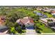 Aerial view showcasing a red-tiled roof home, lush landscaping, and a serene lake in a vibrant neighborhood at 4499 Chase Oaks Dr, Sarasota, FL 34241