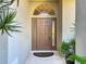 Elegant front door with decorative glass sidelights and a transom window, framed by lush greenery at 4499 Chase Oaks Dr, Sarasota, FL 34241