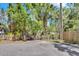 Wooded backyard with gate to the left and fence to the right, next to asphalt road at 57 Hamilton Heath Dr Dr, Tampa, FL 33604
