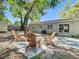 Backyard patio with mature landscaping, and four Adirondack chairs around a concrete paver patio at 7303 N Branch Ave, Tampa, FL 33604