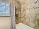 Bathroom featuring a tiled shower, neutral colors, and a window with plantation shutters at 7303 N Branch Ave, Tampa, FL 33604
