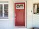 Close-up of a red front door with decorative glass, next to a window with white shutters at 7303 N Branch Ave, Tampa, FL 33604