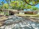 Inviting one-story home featuring a long driveway, carport, and a beautifully shaded front yard at 7303 N Branch Ave, Tampa, FL 33604