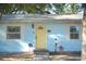 Charming blue home featuring a bright yellow front door with decorative landscaping and window trim at 801 53Rd N Ter, St Petersburg, FL 33703
